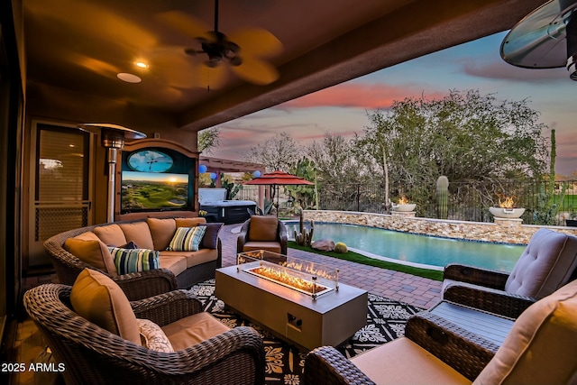 patio terrace at dusk featuring ceiling fan and an outdoor living space with a fire pit