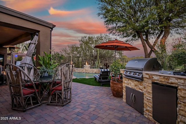 patio terrace at dusk featuring grilling area and exterior kitchen