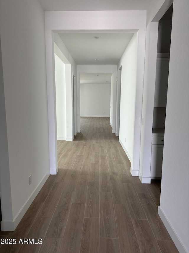 corridor featuring dark wood-type flooring and baseboards