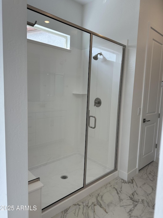 bathroom featuring marble finish floor and a shower stall