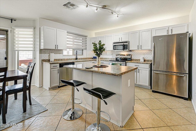 kitchen featuring white cabinets, a kitchen breakfast bar, a center island, light tile patterned floors, and stainless steel appliances