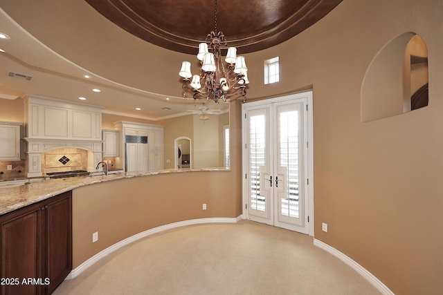 kitchen with light carpet, paneled refrigerator, french doors, a tray ceiling, and decorative backsplash