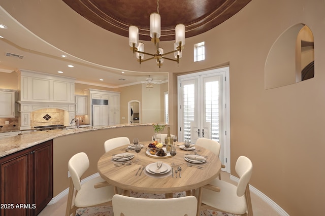 dining space with french doors, sink, a tray ceiling, a notable chandelier, and ornamental molding