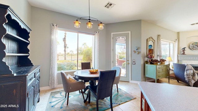 dining space with baseboards, a fireplace, visible vents, and light tile patterned flooring