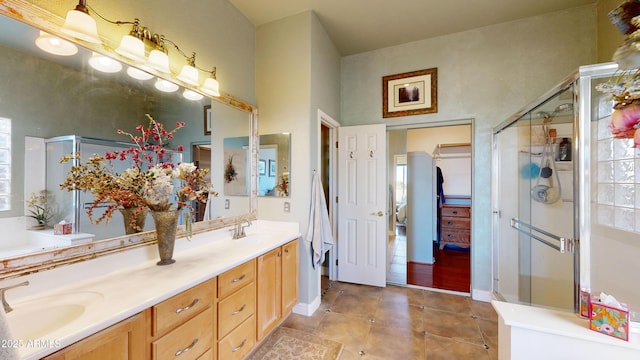 bathroom featuring double vanity, a stall shower, tile patterned flooring, and a sink