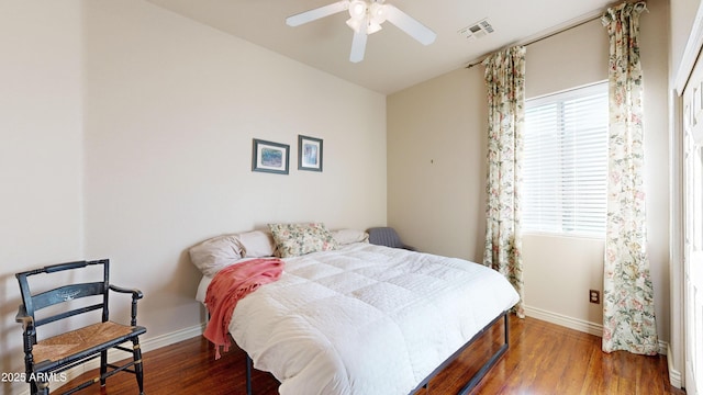 bedroom with a ceiling fan, wood finished floors, visible vents, and baseboards