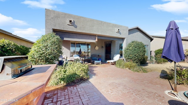 rear view of property with a patio area and stucco siding