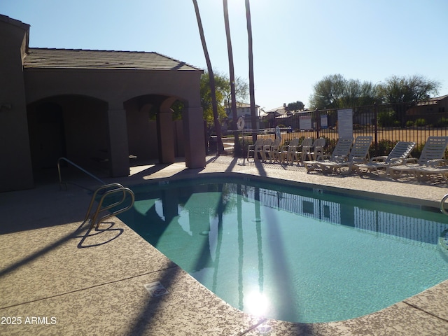 pool with a patio area and fence