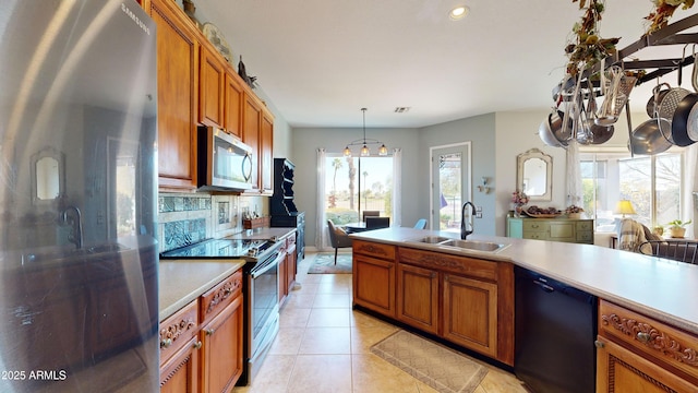 kitchen featuring appliances with stainless steel finishes, brown cabinets, hanging light fixtures, light countertops, and a sink