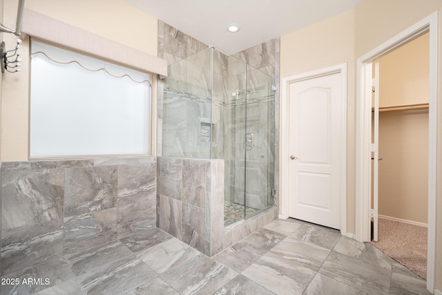 full bath featuring a stall shower, a spacious closet, marble finish floor, and recessed lighting