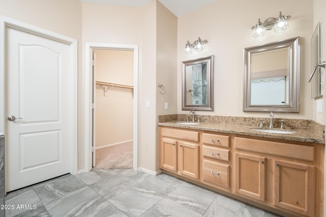 bathroom featuring a sink, a spacious closet, baseboards, and double vanity