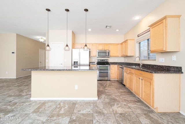 kitchen featuring visible vents, a kitchen island, appliances with stainless steel finishes, light brown cabinetry, and a sink