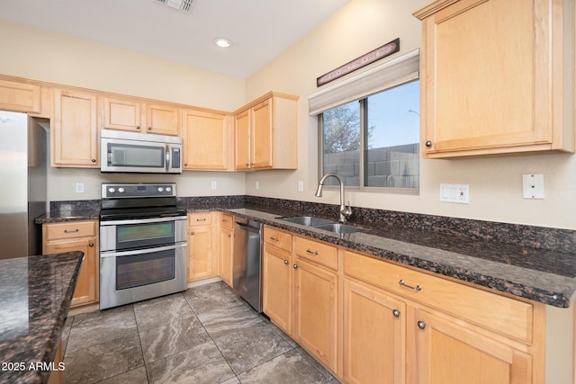 kitchen featuring stainless steel appliances, light brown cabinets, a sink, and visible vents