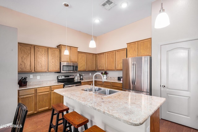 726 E Heather Dr, San Tan Valley, AZ 85140 - kitchen featuring appliances with stainless steel finishes, a sink, dark wood finished floors, a kitchen bar, and brown cabinets