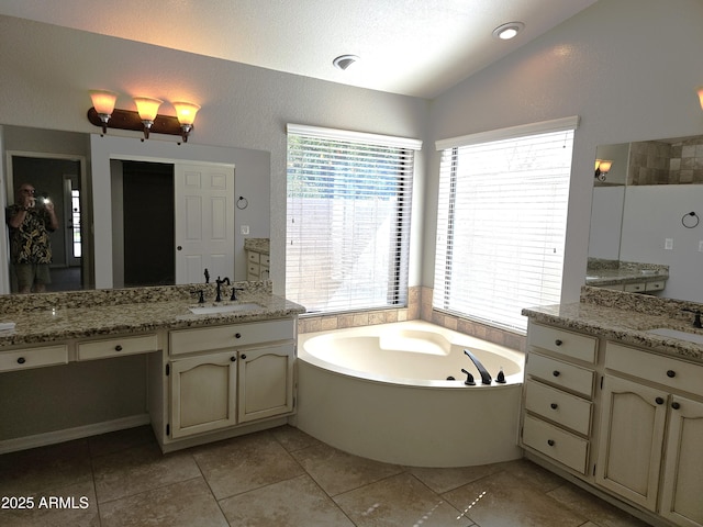 full bathroom with vaulted ceiling, a sink, and a wealth of natural light