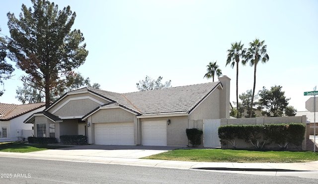 view of front facade featuring an attached garage, a tile roof, driveway, stucco siding, and a front lawn