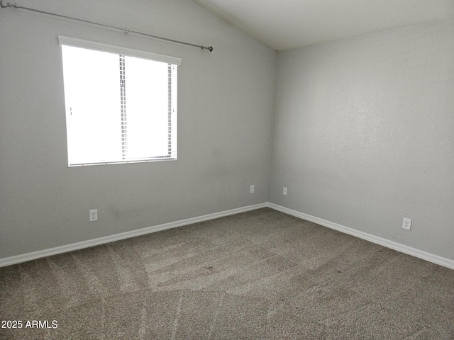 empty room featuring lofted ceiling, carpet flooring, and baseboards