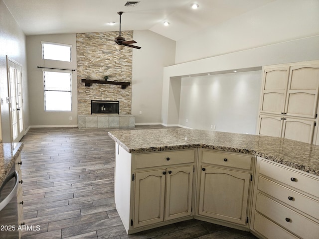 kitchen featuring ceiling fan, cream cabinets, a large fireplace, dark wood-type flooring, and dishwasher