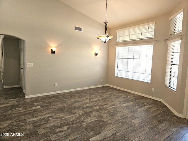 unfurnished room with baseboards, arched walkways, visible vents, dark wood-style flooring, and vaulted ceiling