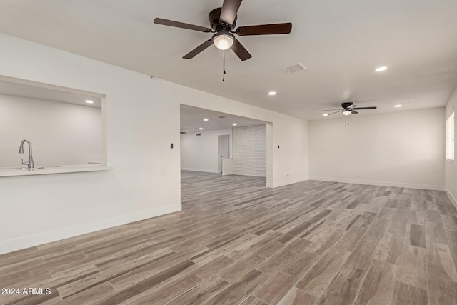 unfurnished living room with ceiling fan, light hardwood / wood-style floors, and sink