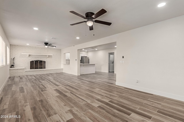 unfurnished living room featuring a fireplace, wood-type flooring, and ceiling fan