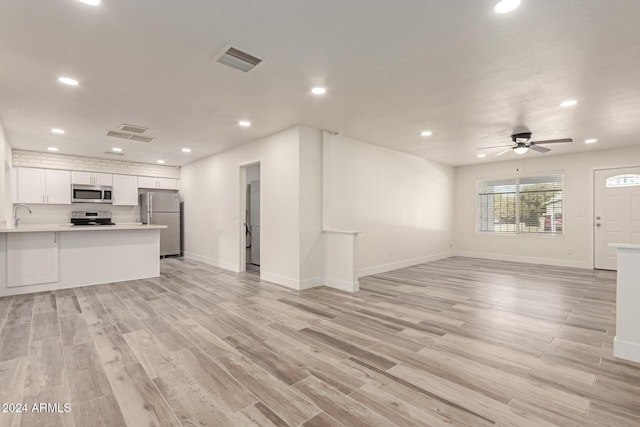 unfurnished living room with light hardwood / wood-style floors, ceiling fan, and sink