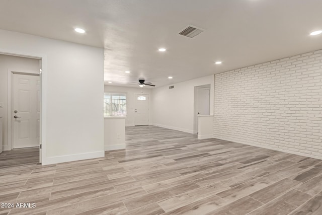 spare room with ceiling fan, light hardwood / wood-style floors, and brick wall