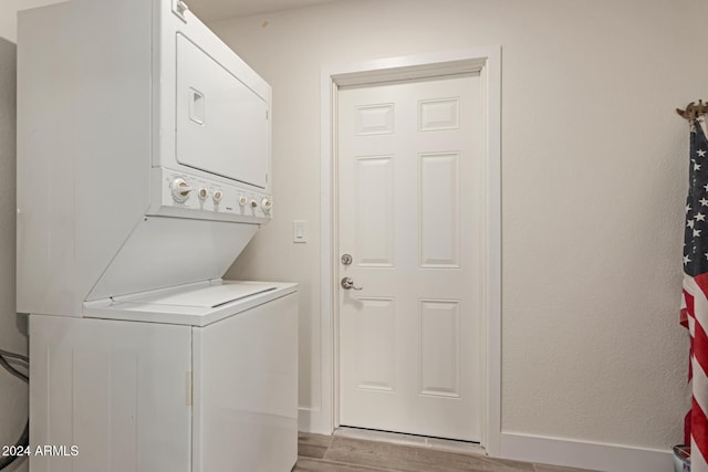 laundry room with stacked washer / drying machine and light wood-type flooring