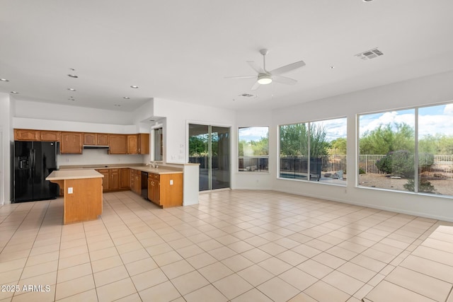 kitchen with a healthy amount of sunlight, open floor plan, a ceiling fan, light countertops, and black appliances