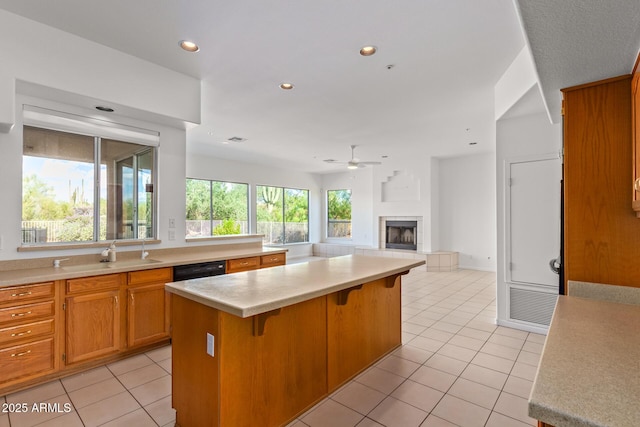 kitchen with light countertops, a sink, light tile patterned floors, and a ceiling fan