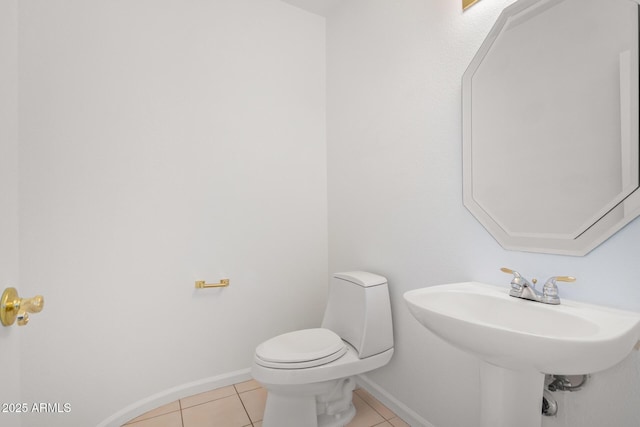 bathroom featuring toilet, tile patterned floors, and baseboards