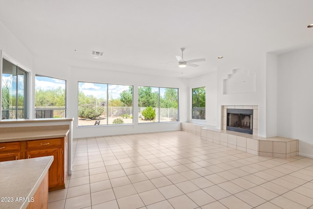 unfurnished living room featuring visible vents, light tile patterned flooring, ceiling fan, a tile fireplace, and baseboards