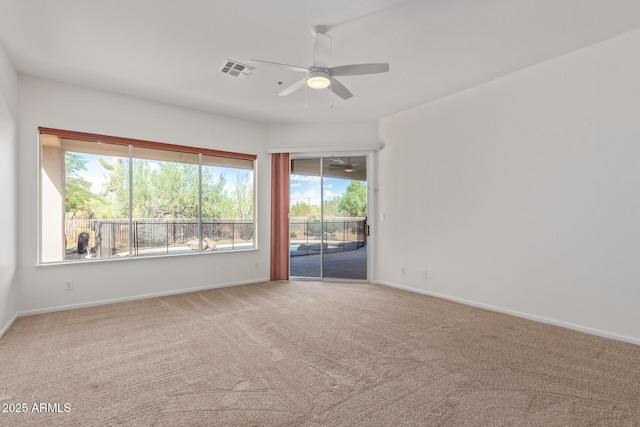 carpeted empty room with ceiling fan, baseboards, visible vents, and plenty of natural light