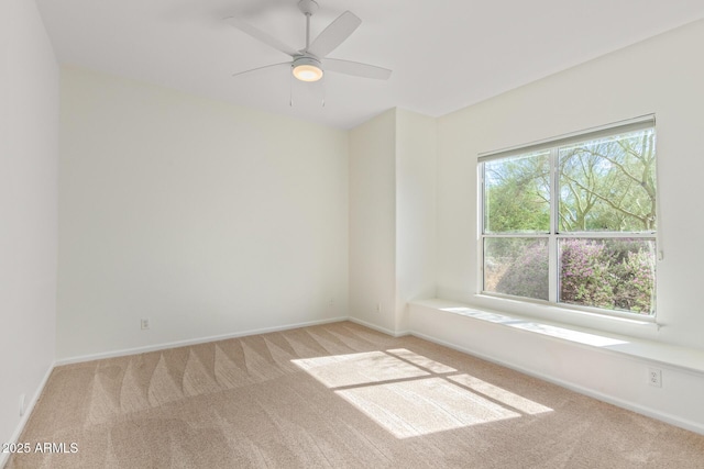 carpeted spare room featuring ceiling fan and baseboards