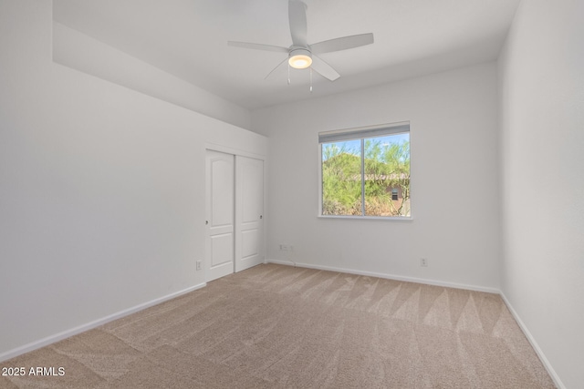spare room with carpet floors, a ceiling fan, and baseboards