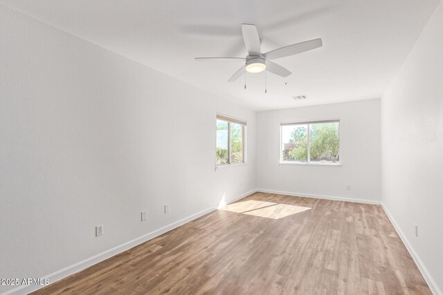 unfurnished room featuring baseboards, light wood-style floors, and visible vents