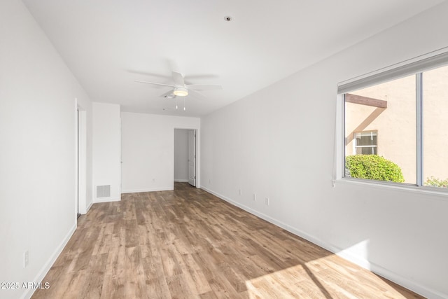 unfurnished room featuring a wealth of natural light, wood finished floors, visible vents, and baseboards