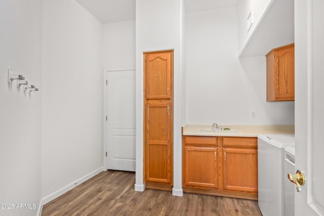 washroom with light wood-style flooring, a sink, baseboards, separate washer and dryer, and cabinet space