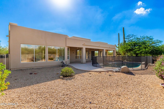 back of house with stucco siding, a fenced in pool, a patio, and fence