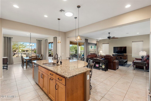 kitchen featuring pendant lighting, ceiling fan with notable chandelier, light stone counters, and sink