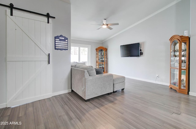 unfurnished living room featuring a barn door, wood finished floors, ornamental molding, and a ceiling fan