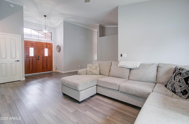 living area featuring visible vents, baseboards, wood finished floors, and crown molding