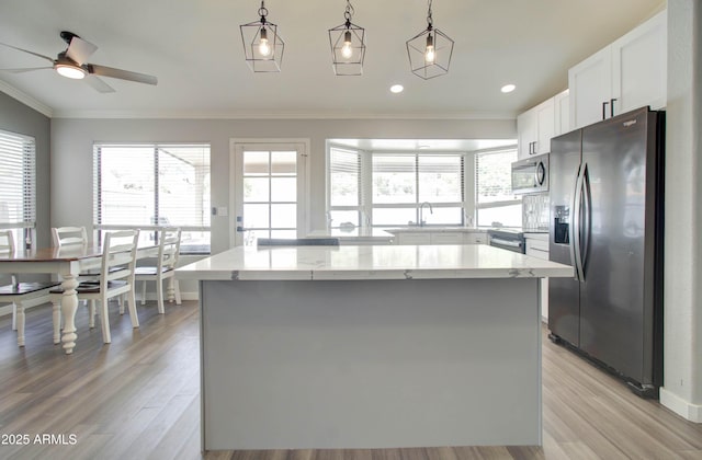 kitchen featuring crown molding, a center island, a wealth of natural light, and stainless steel appliances