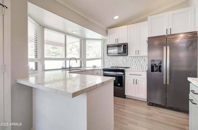 kitchen featuring a sink, backsplash, stainless steel appliances, a peninsula, and lofted ceiling