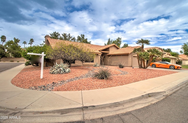 view of front facade featuring a tiled roof, stucco siding, an attached garage, and driveway