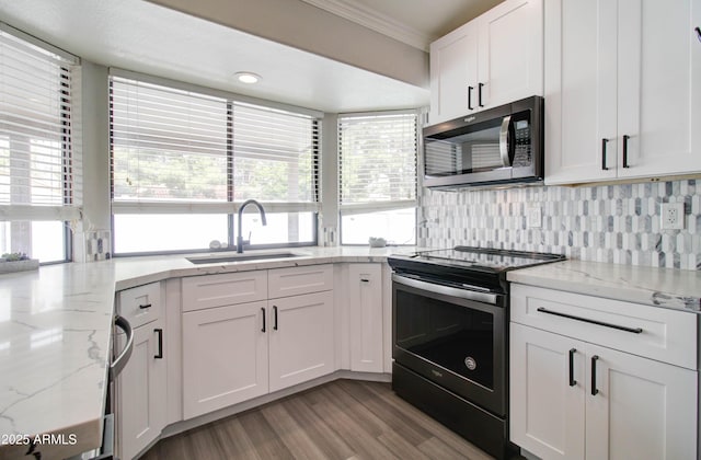 kitchen featuring stainless steel microwave, crown molding, electric range, white cabinetry, and a sink