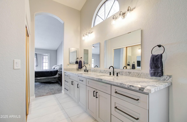 ensuite bathroom featuring a sink, connected bathroom, double vanity, and tile patterned floors