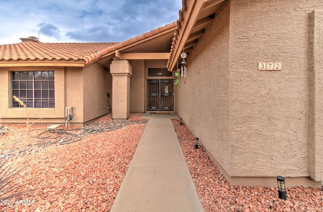 view of exterior entry featuring a tiled roof and stucco siding