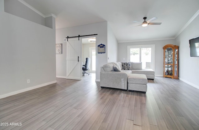 living area with a barn door, crown molding, wood finished floors, and ceiling fan