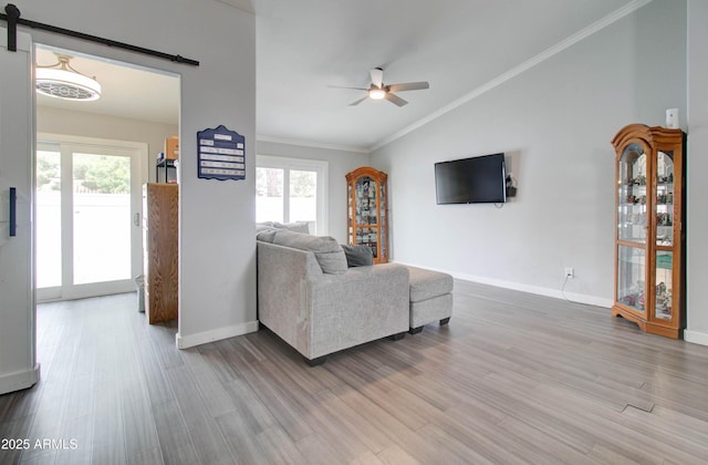 living area with a barn door, wood finished floors, a ceiling fan, and a wealth of natural light